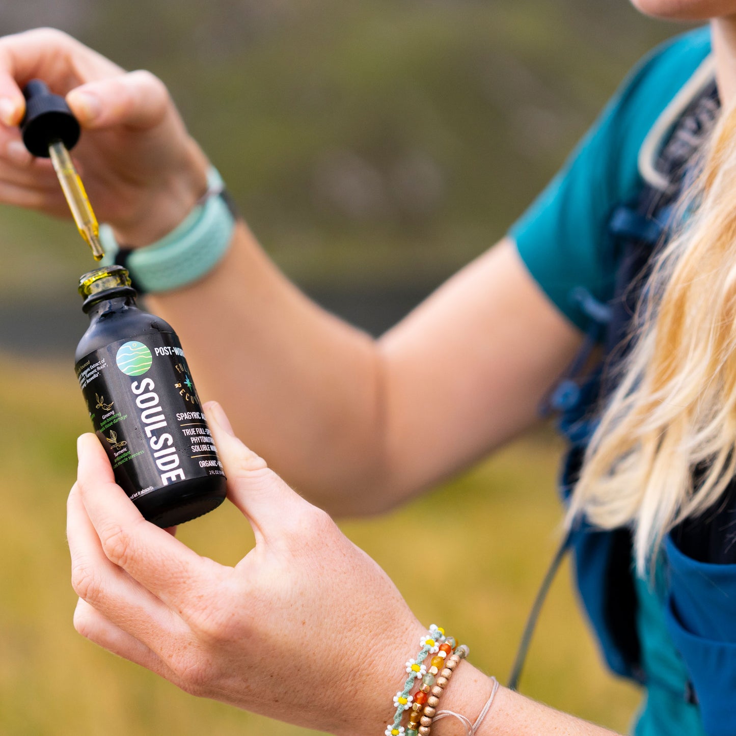 Image of trail runner holding Soulside Full Recovery herbal tincture, an organic herbal supplement to help with inflammation, muscle recovery, muscle soreness, immunity and brain health.